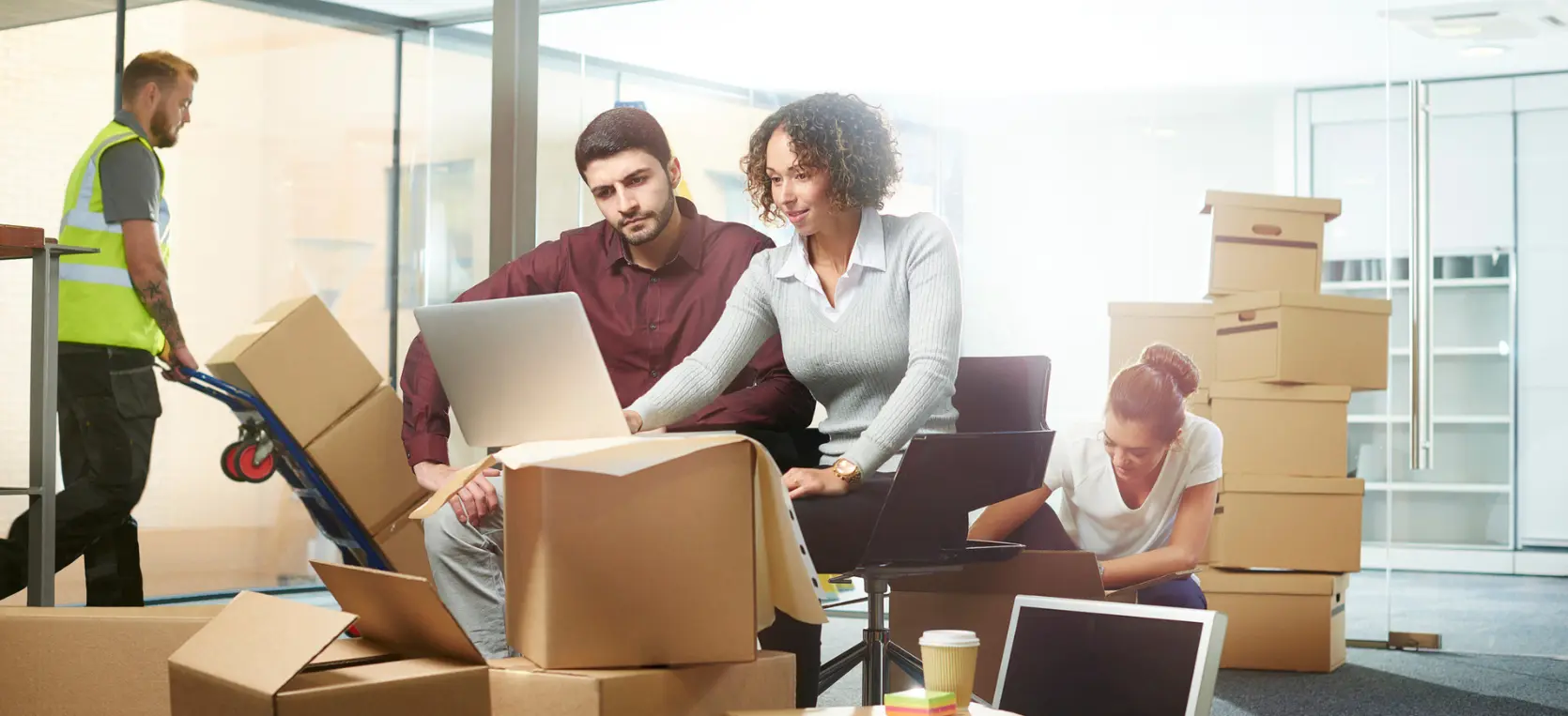 couple looking at laptop in office space surrounded by moving boxes
